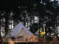 En vit glampingtält står redo för äventyr i en svensk skog. Mysigt och naturnära glamping i Sverige.