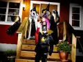 Barn utklädda till häxor och Batman förbereder sig för halloween helg. En svart katt smyger på trappan.