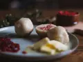 En tallrik med pitepalt, lingonsylt och smör. En halv palt visar en fyllning av fläsk. Perfekt för ett recept på pitepalt.