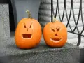 Två utskurna pumpor med läskiga ansikten står redo för halloween vecka.