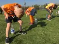 Barn i orange kläder böjer sig framåt för att försöka fånga en flaska med munnen. En del av kalas lekarna.