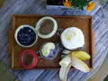 En bricka med ingredienser för sommarmat recept: blåbär, yoghurt, banan och en burk med bär och banan.