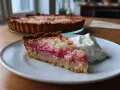 En saftig bit glutenfri rabarberpaj med en klick vispad grädde. Pajen har en gyllene botten och fyllning med rosa rabarberbitar.