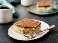 En bit vanilj bakelser med chokladglasyr på en tallrik, redo att avnjutas med en kopp kaffe.