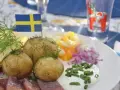 En tallrik med sill, färskpotatis, ost och dill. En svensk flagga vajar stolt. Perfekt mat midsommar!