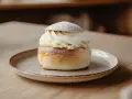 En semla med rikligt med vispad grädde och mandelmassa till semlor, pudrad med florsocker.