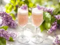 Två glas med rosa bubbel, dekorerade med syrenblommor. Perfekt för ett syrensirap recept.