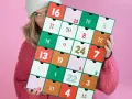 En person med en stickad tröja och mössa håller upp en färgglad julkalender. En perfekt julkalender diy att skapa själv!