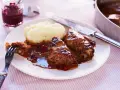 Kåldolmar recept: två saftiga kåldolmar med potatismos och lingonsylt, serverade med en mustig sås.