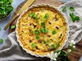 En gyllene kantarellpaj, perfekt för ett höstligt kantarellpaj recept. Garnerad med färska gröna blad och serverad med en gyllene kniv.