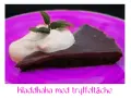 En bit kladdkaka med vispgrädde och mynta på en lila tallrik. Perfekt för en kladdkaka dag!