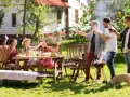 Vänner njuter av grillfest och lekar till 5 kamp i trädgården. En liten gris nosar i gräset.