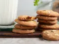 En hög med mandelkakor, perfekta för ett bondkakor recept, bredvid ett glas mjölk.