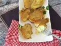 Krispiga, gyllene smashed potatis på en vit tallrik, garnerade med persilja. En gaffel visar en mjuk insida.