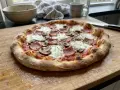 En härlig hemmagjord pizza med skinka och champinjoner, redo att avnjutas.