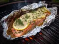 En saftig grillad laxsida i folie, toppad med citronskivor och dill, ångar på grillen.