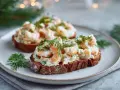 Två toast Skagen på mörkt bröd, toppade med räkor, majonnäs och dill. En klassisk svensk delikatess.
