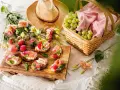 En härlig picknick med bruschetta toppad med jordgubbar och parmaskinka, färska jordgubbar, vindruvor i korg och en stråhatt.