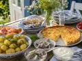 En härlig midsommar afton-buffé med sill, lax, färskpotatis, paj och jordgubbar dukas upp utomhus.
