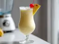 En krämig pina colada i ett glas, garnerad med ananas och ett körsbär. Perfekt för en solig dag!