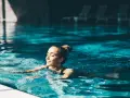 Avslappnad kvinna njuter av ett lugnt bad i en inomhuspool, en perfekt bild av spa i Sverige.