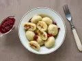 En skål med kroppkakor, en klassisk svensk rätt, serveras med lingonsylt. Recept på kroppkakor finns här.
