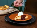 En bit ostkaka med vispad grädde och sylt. Ett perfekt ostkaka recept för fikat.