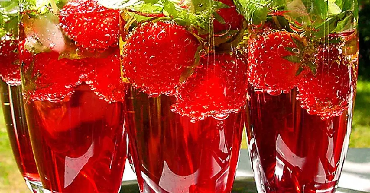 Tre glas med röd midsommar drink fyllda med jordgubbar och mynta. Bubbligt och uppfriskande.