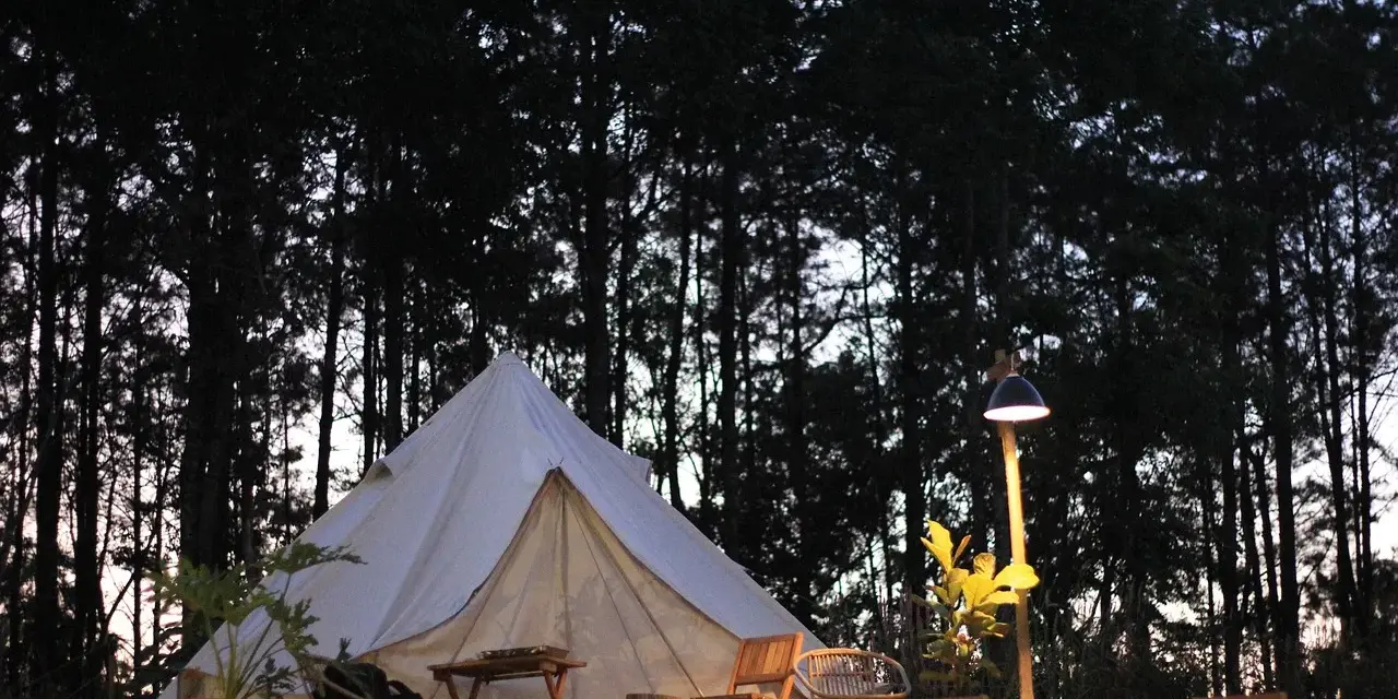 En vit glampingtält står redo för äventyr i en svensk skog. Mysigt och naturnära glamping i Sverige.