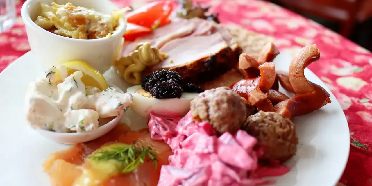 En tallrik med julbordsfavoriter: sill, köttbullar, prinskorv, ägg, rom och skinka. En perfekt checklista för julbordet!