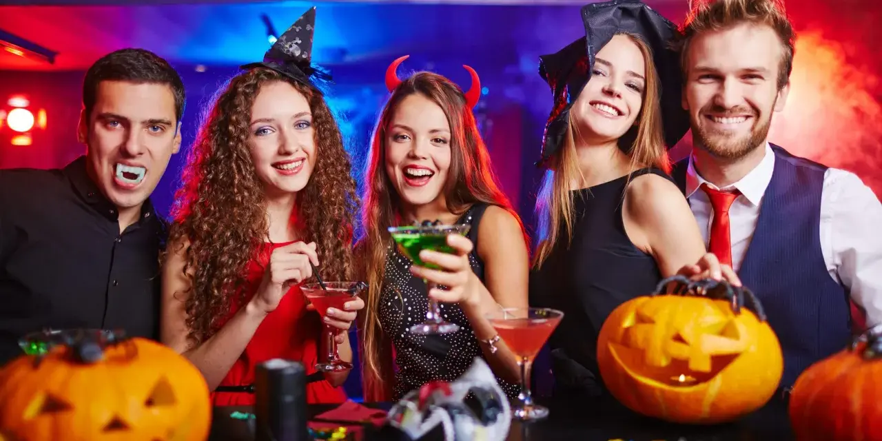 Glada vuxna firar halloween med drinkar och pumpor. En vampyr, en häxa och en djävul njuter av festen. Perfekt för halloween lekar vuxna!