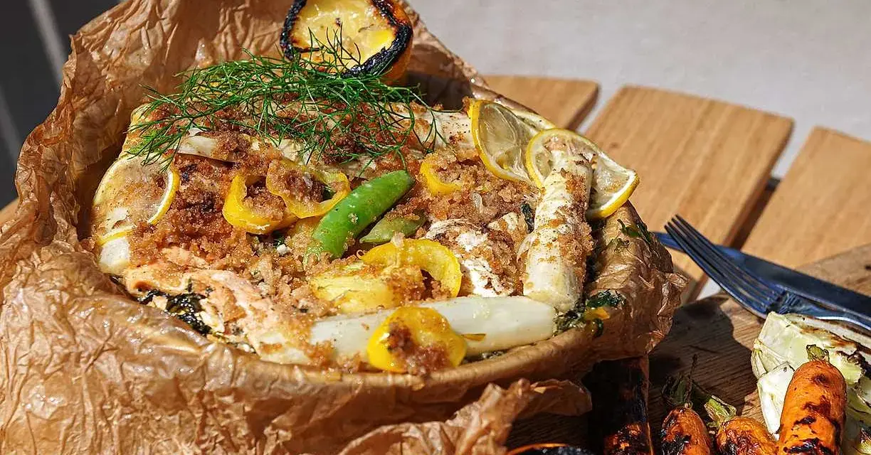 En saftig fiskpaket på grillen med citron, sparris och dill. Serveras med grillade grönsaker.