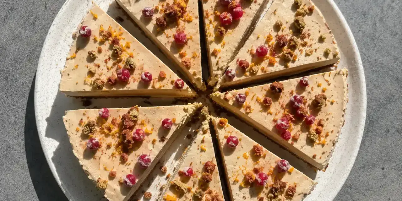 En skivad pepparkakscheesecake med lingon, garnerad med smulor och apelsinzest. En härlig juldessert!