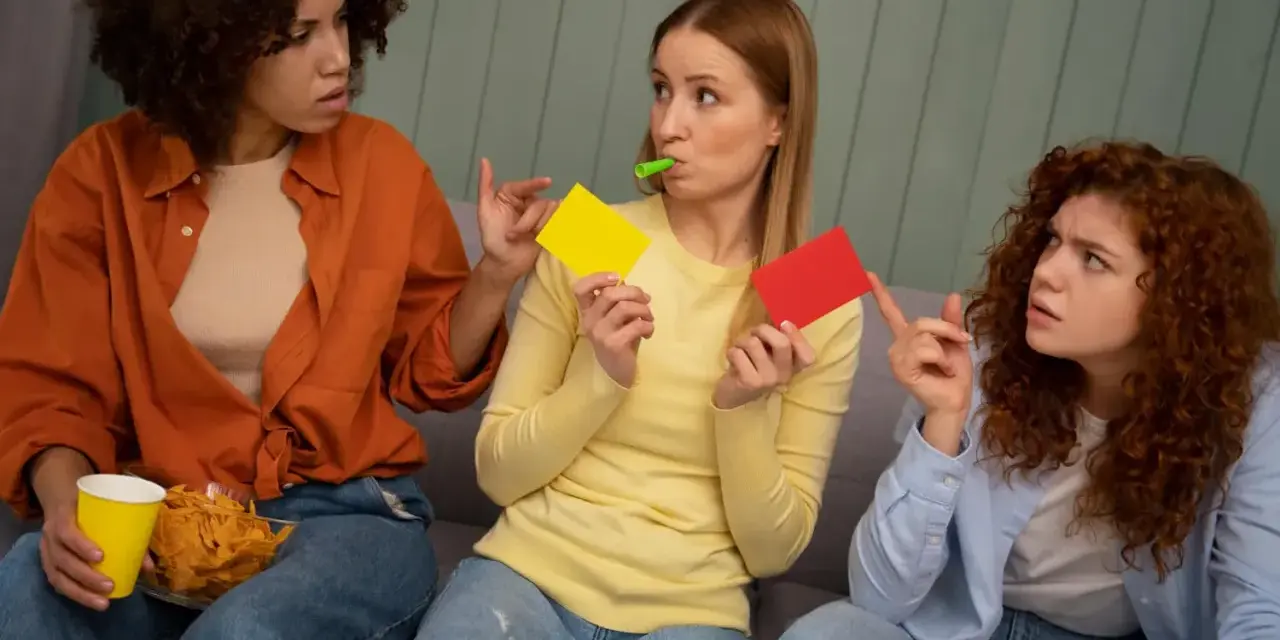Tre vänner spelar par med en lek, en med gul och röd kort, en med chips och en med visselpipa.