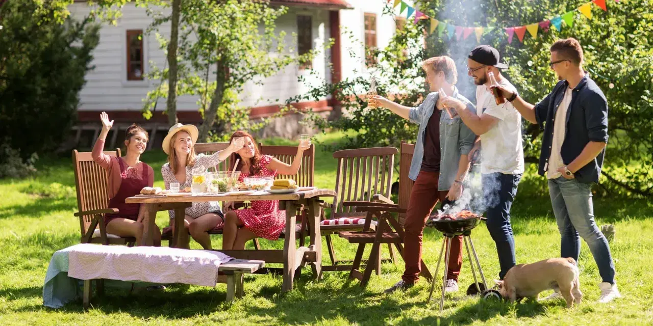 Vänner njuter av grillfest och lekar till 5 kamp i trädgården. En liten gris nosar i gräset.