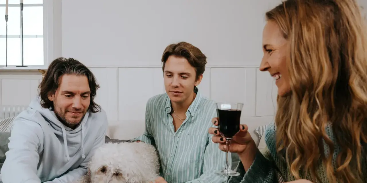 Familj spelar julklappsspelet. Alla får en julklapp, men reglerna kan vara knepiga! En vit hund vilar på soffan.
