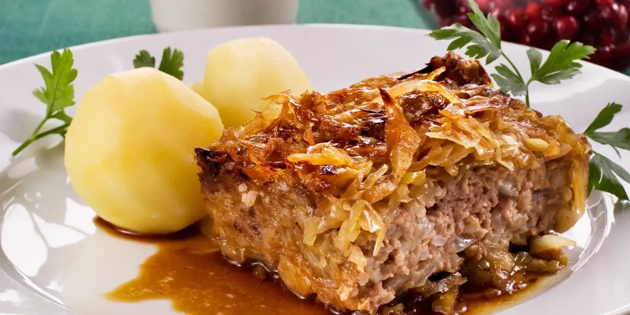 En bit kålpudding med kokt potatis och en skvätt sås. Perfekt för ett klassiskt kålpudding recept.