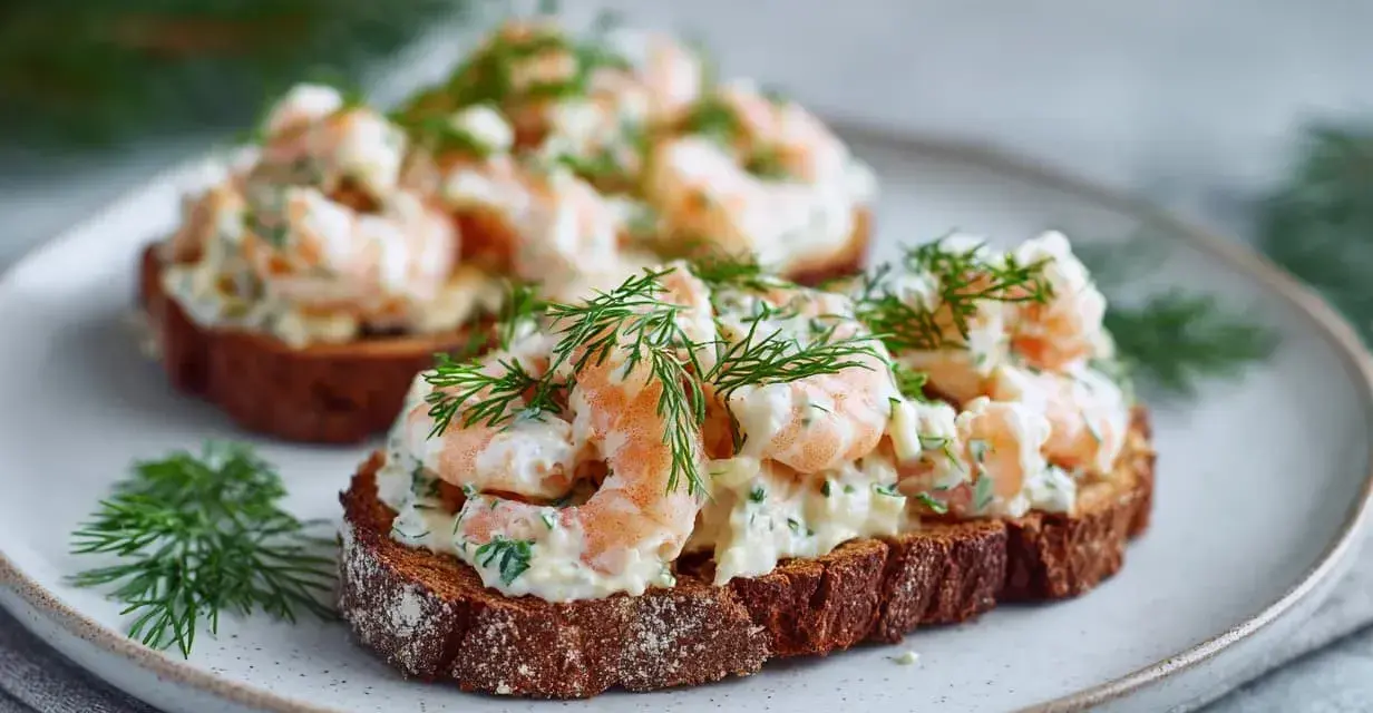 Två toast Skagen på mörkt bröd, toppade med räkor, majonnäs och dill. En klassisk svensk delikatess.