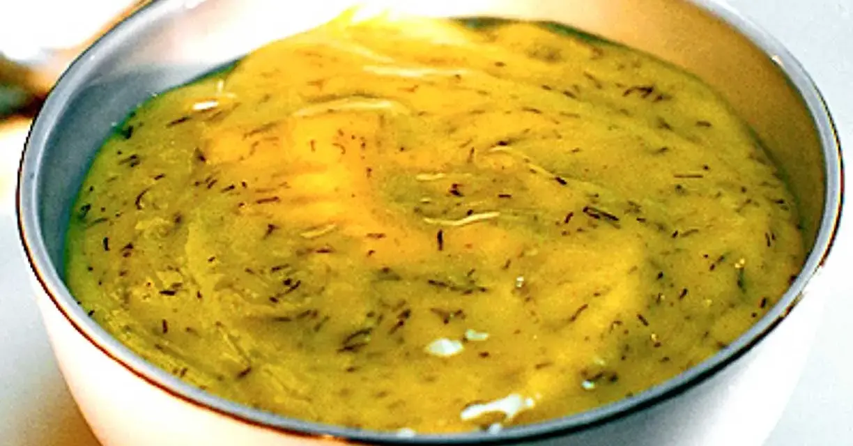 En skål med krämig gravlaxsås, perfekt för ditt gravlaxsås recept. Dill och senap syns i den gula såsen.