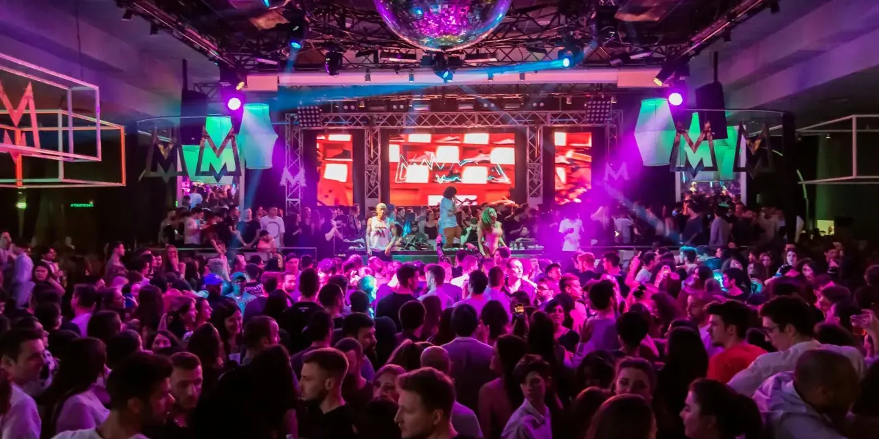 Folk dansar och festar på en 30-årsfest. En discokula hänger i taket och scenen lyses upp av färgglada lampor.