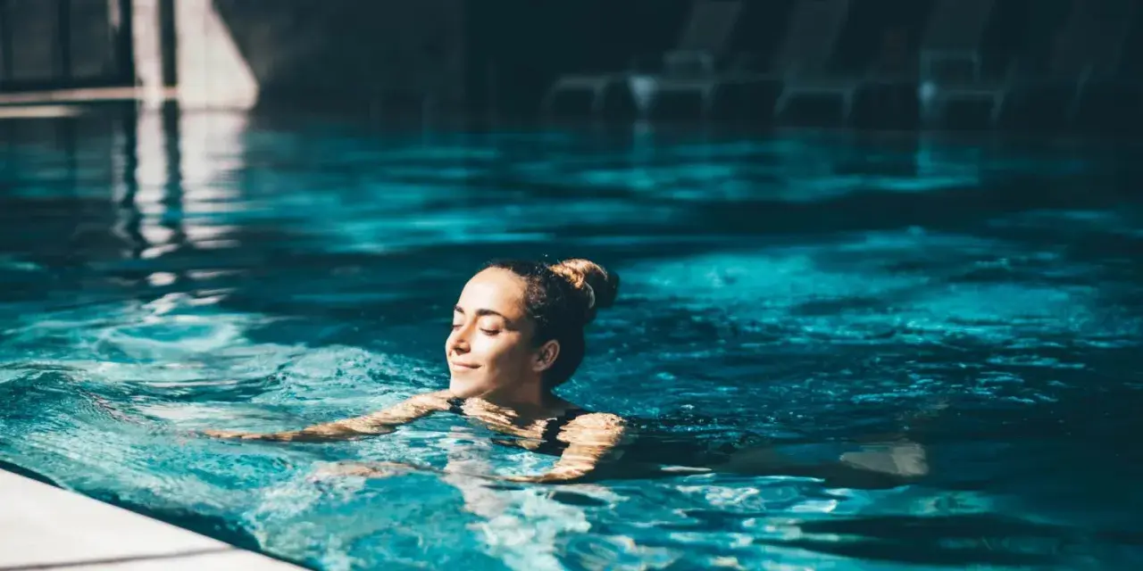 Avslappnad kvinna njuter av ett lugnt bad i en inomhuspool, en perfekt bild av spa i Sverige.