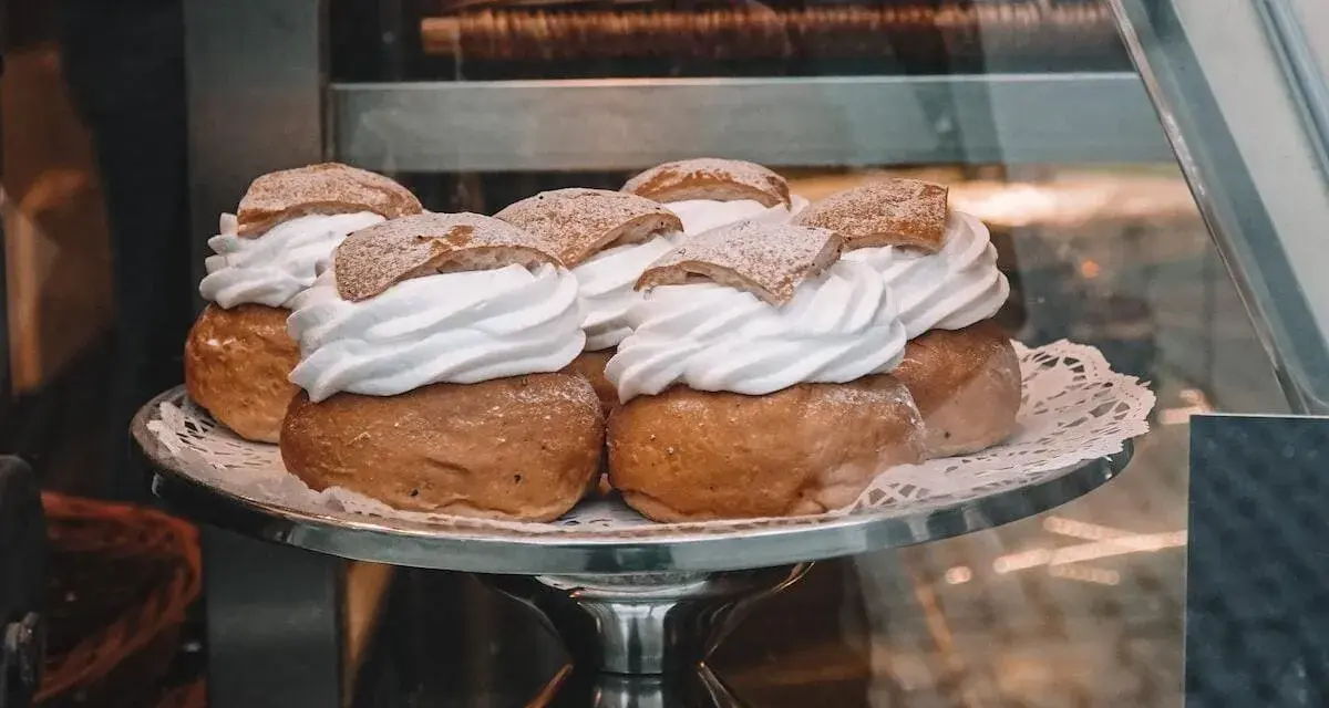 Sju semlor på ett fat, redo för pannkakans dag. Krämig grädde och pudrat socker.