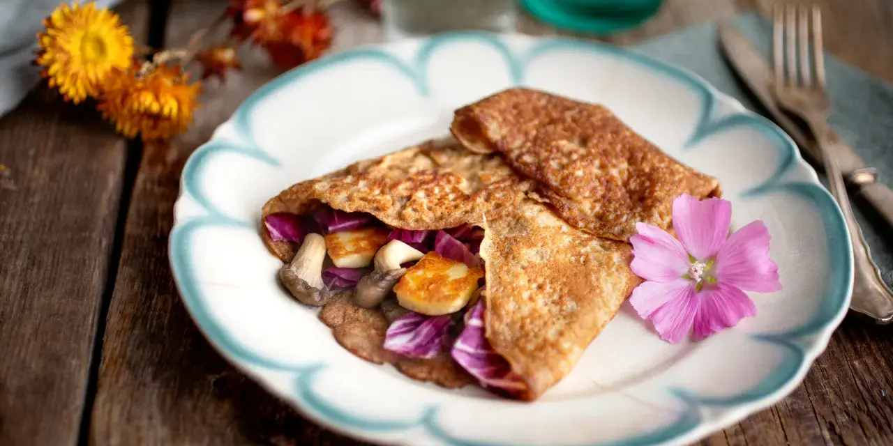Matiga pannkakor fyllda med svamp, halloumi och rödkål, dekorerade med en rosa blomma.