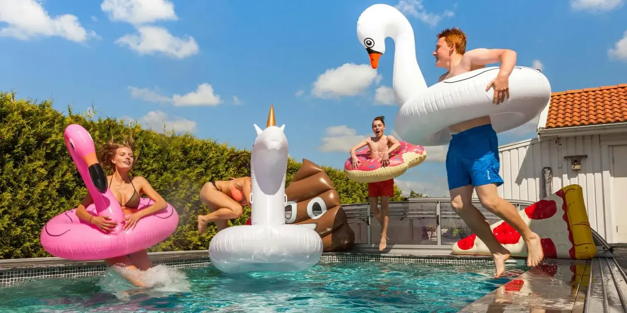 Ungdomar hoppar i poolen med uppblåsbara badleksaker som flamingo, enhörning och bajskorv. Perfekt för midsommarlekar inomhus eller utomhus!