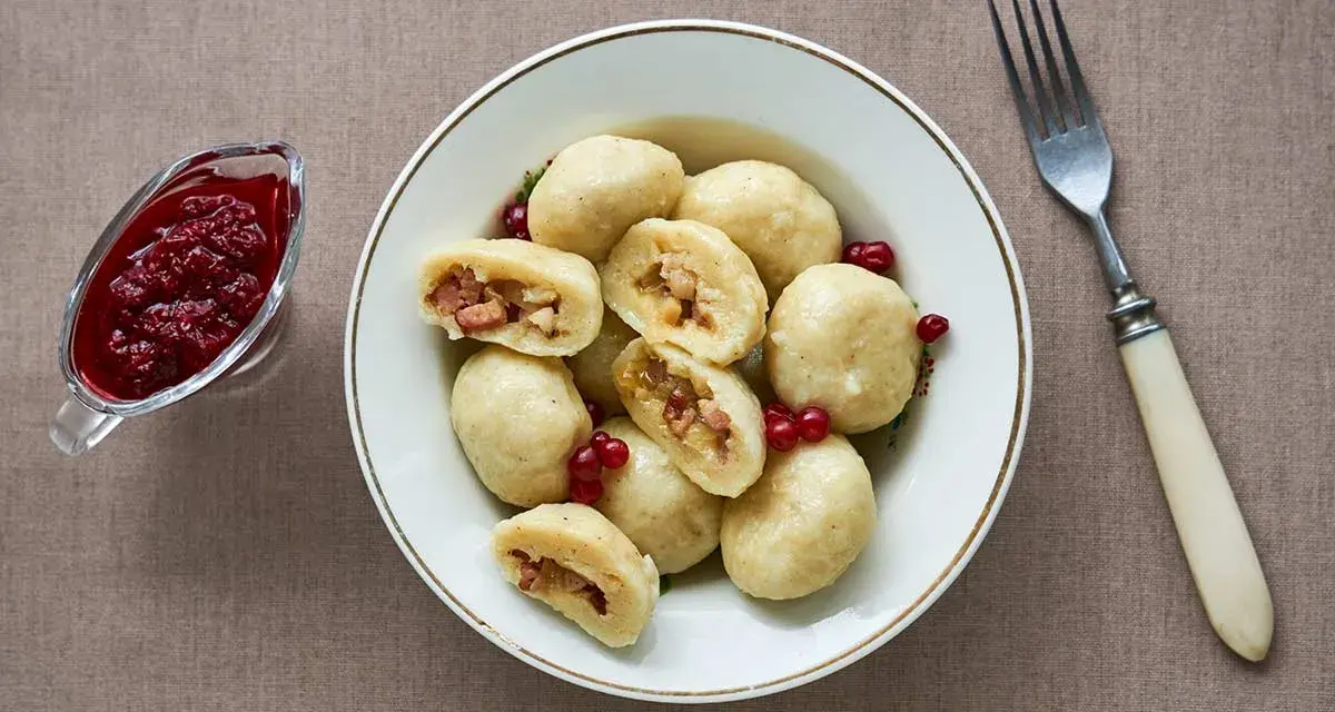 En skål med kroppkakor, en klassisk svensk rätt, serveras med lingonsylt. Recept på kroppkakor finns här.
