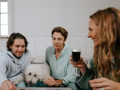 Familj spelar julklappsspelet. Alla får en julklapp, men reglerna kan vara knepiga! En vit hund vilar på soffan.