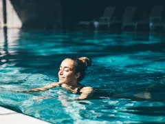 Avslappnad kvinna njuter av ett lugnt bad i en inomhuspool, en perfekt bild av spa i Sverige.