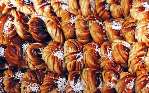 En stor hög med gyllene kanelbullar, perfekta för kanelbullens dag. Strösslade med pärlsocker.