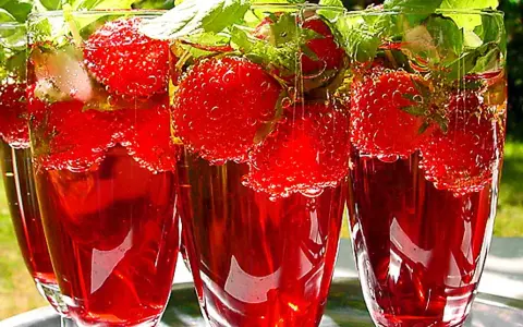 Tre glas med röd midsommar drink fyllda med jordgubbar och mynta. Bubbligt och uppfriskande.