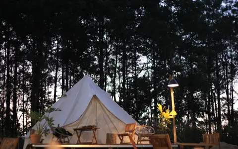 En vit glampingtält står redo för äventyr i en svensk skog. Mysigt och naturnära glamping i Sverige.
